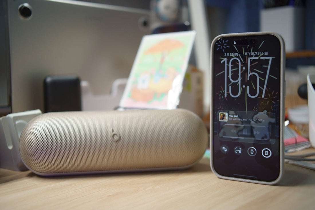 Smartphone and speaker on a wooden desk.
